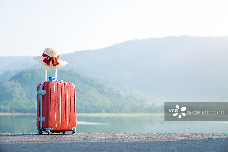 以自然为背景的红色旅行箱，度假旅游理念。图片素材