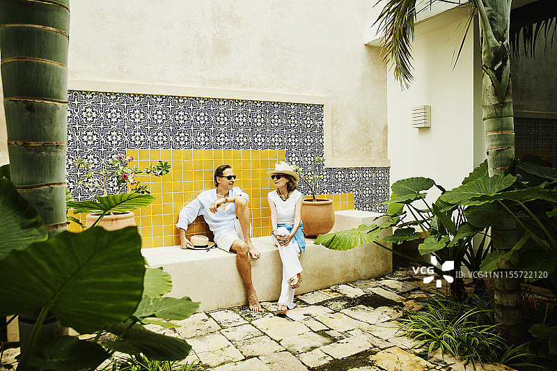 在热带度假胜地的庭院里放松的老夫妇肖像图片素材