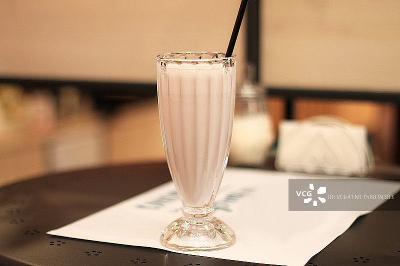 一款美味的草莓奶昔，在咖啡厅的桌子上，用高脚杯盛着。图片素材