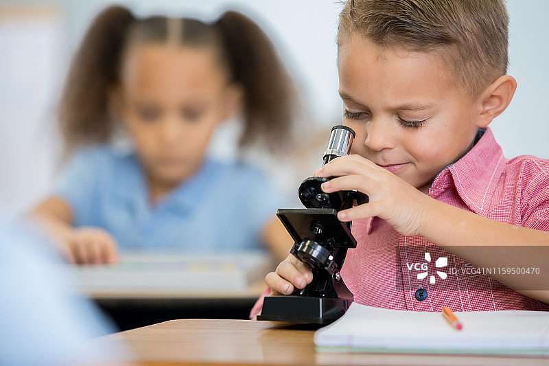 一个小学的小男孩正在小学的STEM课堂上使用显微镜图片素材