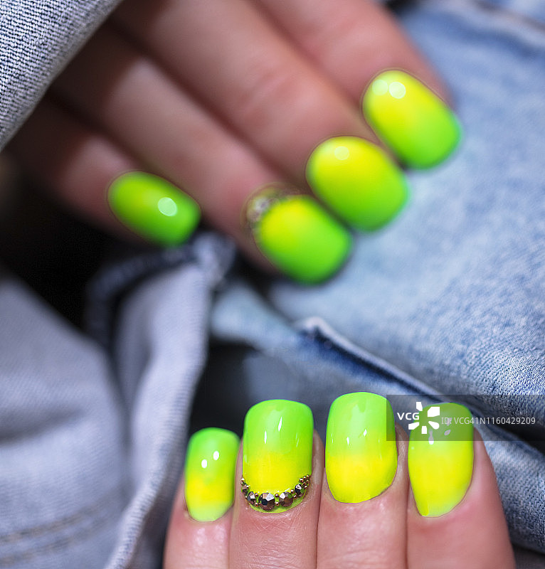 特写的女人的手指与指甲艺术美甲与霓虹灯绿色图片素材