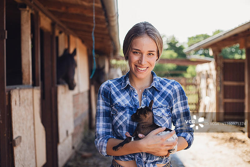 露齿微笑的女牛仔和她新生的小山羊图片素材