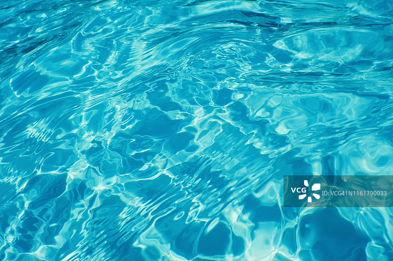 游泳池水中阳光反射的背景。水波纹。图片素材