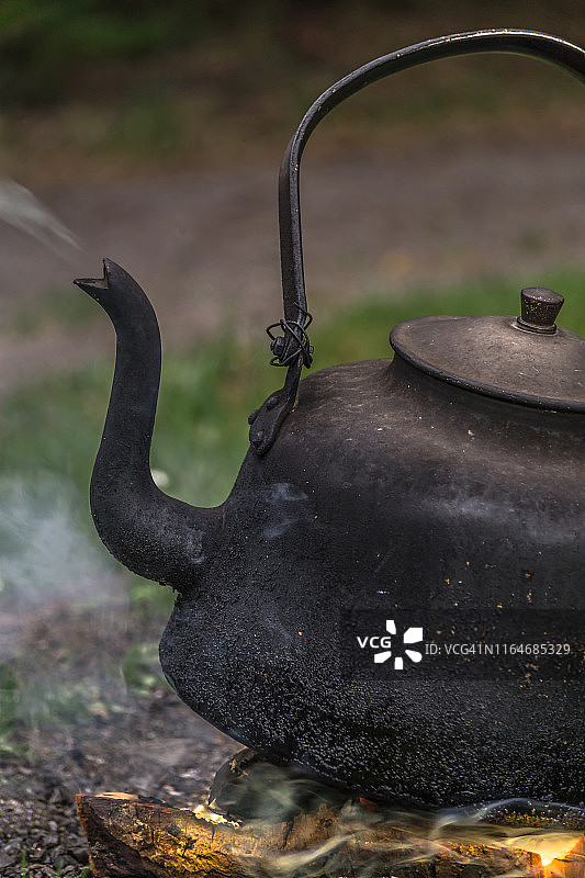 旧铁壶在篝火上加热。图片素材