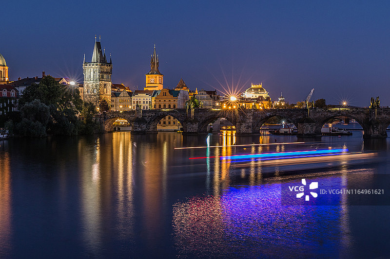 查尔斯大桥和老城塔的夜晚，伏尔塔瓦河的倒影和船上的灯光图片素材