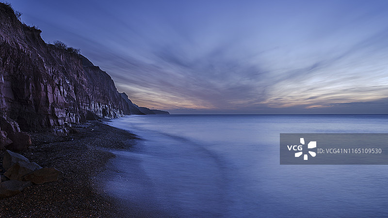 后退的波浪在悬崖下的风景如画的海边小镇Sidmouth，德文郡，英格兰，英国，欧洲图片素材