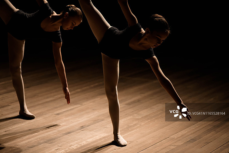柔韧的芭蕾舞演员在昏暗的灯光下伸展四肢图片素材