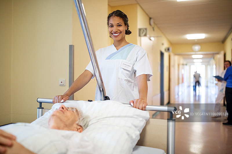 护士推着一位老年病人上轮床图片素材