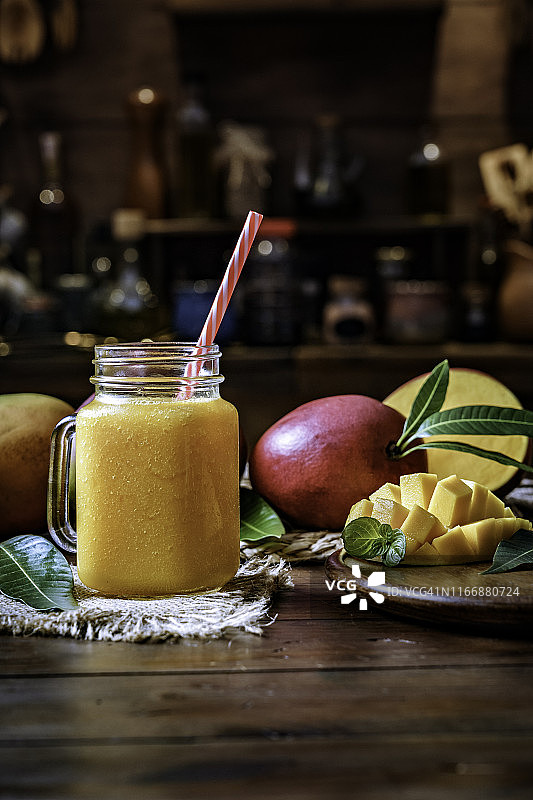 在乡村厨房的木桌上放着芒果果汁和水果玻璃杯图片素材
