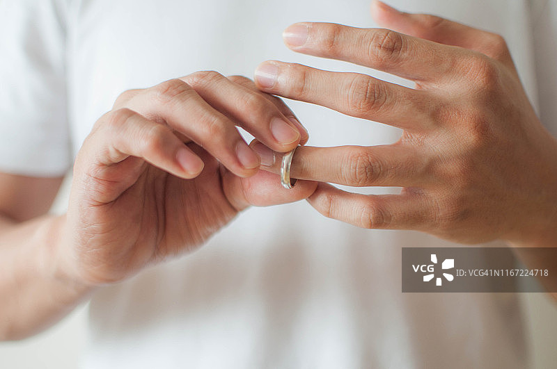 一个年轻人正在摘掉他的结婚戒指一个概念的关系困难图片素材
