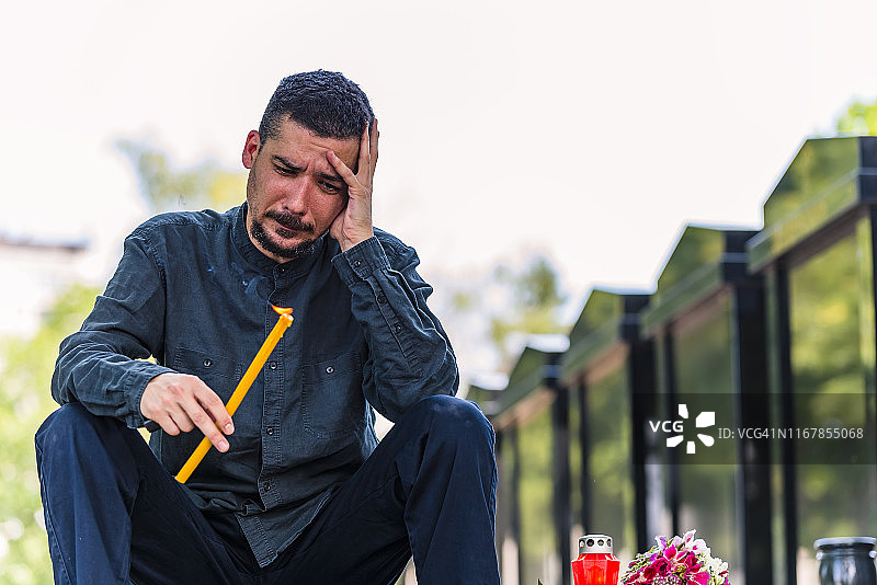 在墓地上拿着蜡烛的情绪紧张的男人图片素材