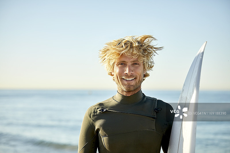 带着冲浪板的微笑男子的肖像图片素材