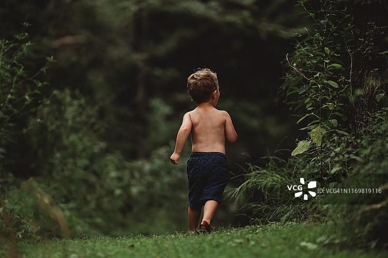在森林里奔跑的孩子的背部图片素材