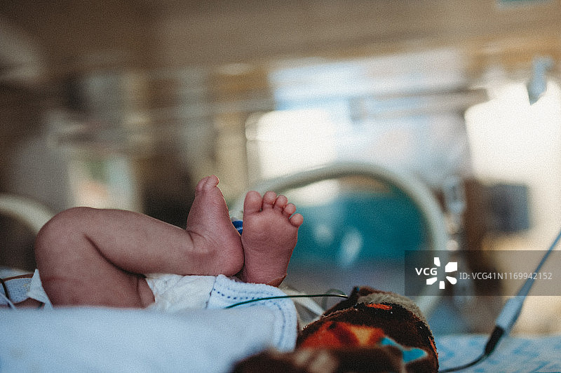 足部特写早产儿睡在新生儿重症监护室里，用氧气管和喂食管图片素材