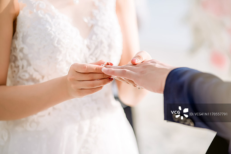 结婚戒指。她给他戴上了结婚戒指。近距离新娘给新郎戴上戒指。婚礼仪式和婚礼装饰。图片素材