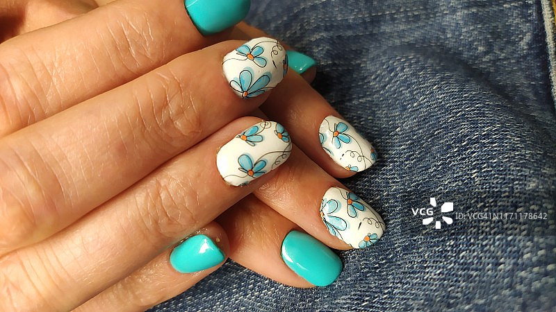 特写的女人手指与指甲艺术美甲在蓝色图片素材