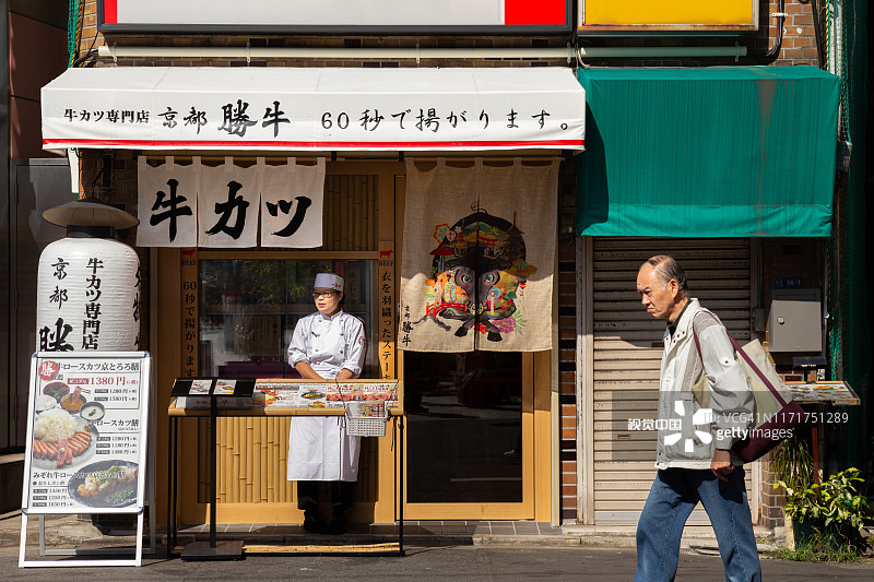 一位亚洲老人走在街上，而日本女经理试图邀请顾客在东京当地的日本餐厅吃早餐或午餐，图片素材