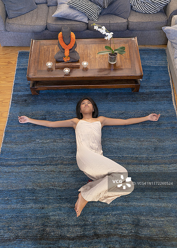 亚洲妇女在地毯上练习瑜伽图片素材
