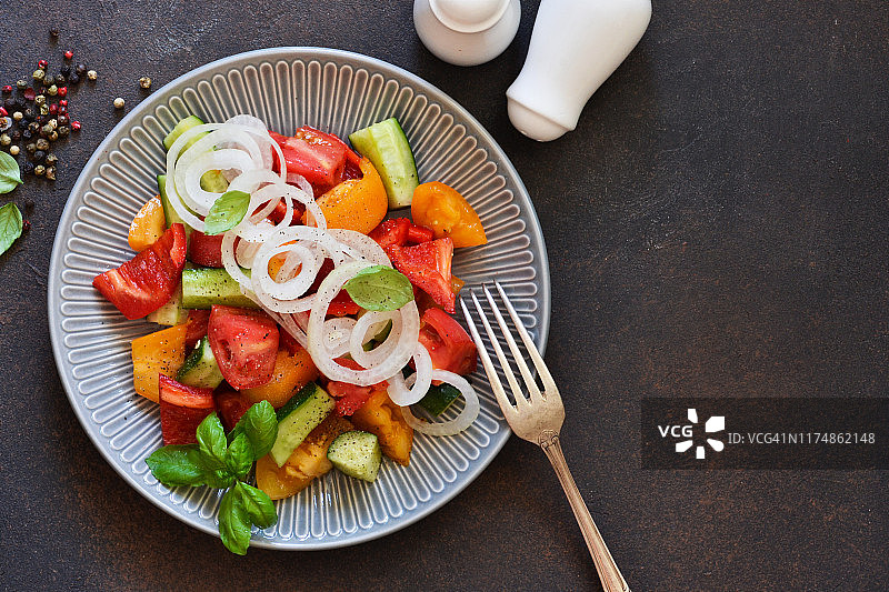 蔬菜沙拉，有西红柿，辣椒和洋葱在厨房的桌子上。从以上观点。图片素材