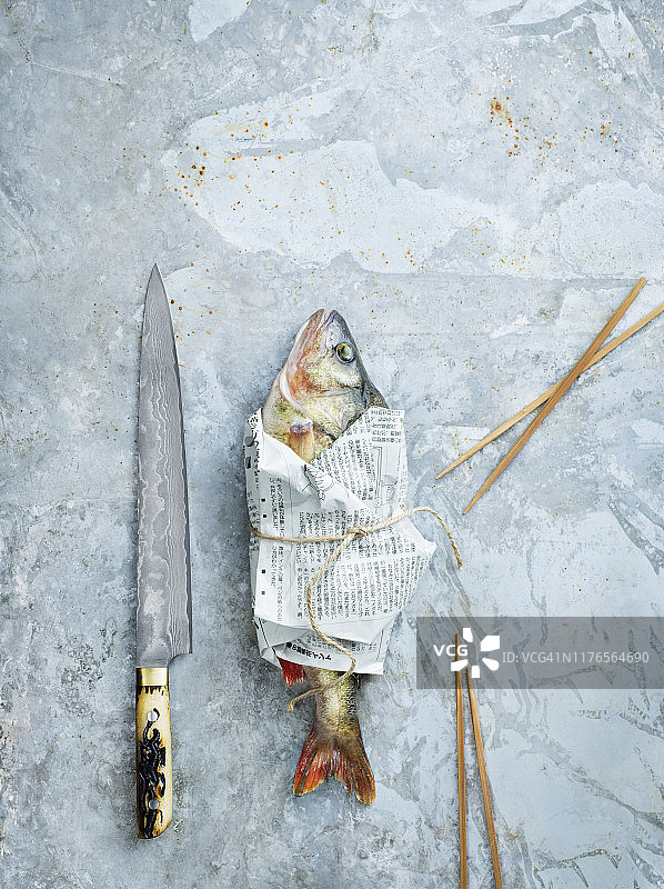 刀子和用报纸包起来的生鱼图片素材