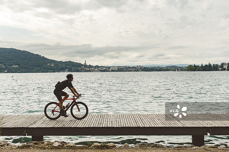 在安纳西湖边的木制码头上骑自行车的人图片素材