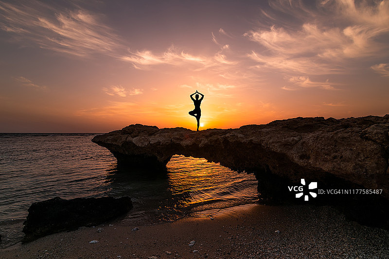 女人剪影做瑜伽锻炼在日落海滩图片素材