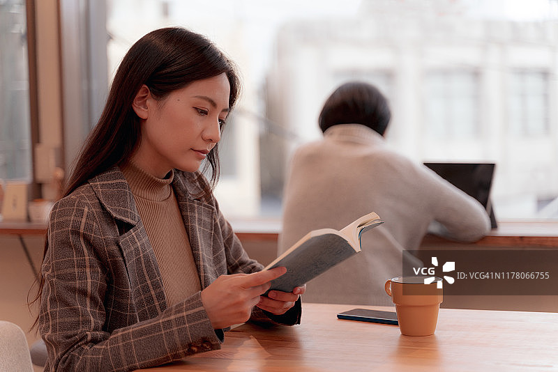 生活在日本的年轻女性在一个安静的空间里的咖啡馆里读书图片素材