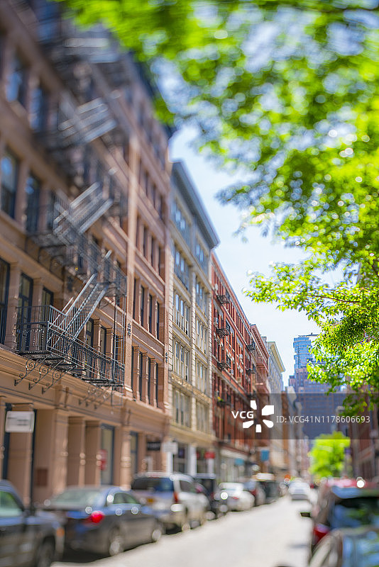 2019年5月18日，在美国纽约SOHO区，一排排Loft公寓建筑矗立在石头人行道街道两侧，远处生长着新鲜的绿叶树。图片素材