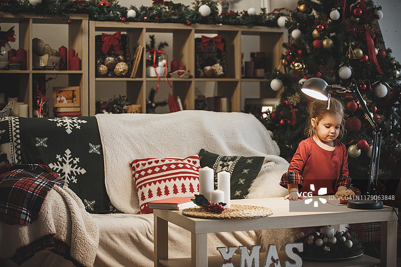 圣诞节前夕，一个女孩站在客厅里吃松饼图片素材