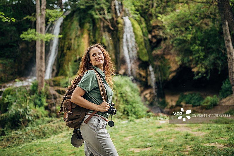 带着相机的女人置身于瀑布之中图片素材