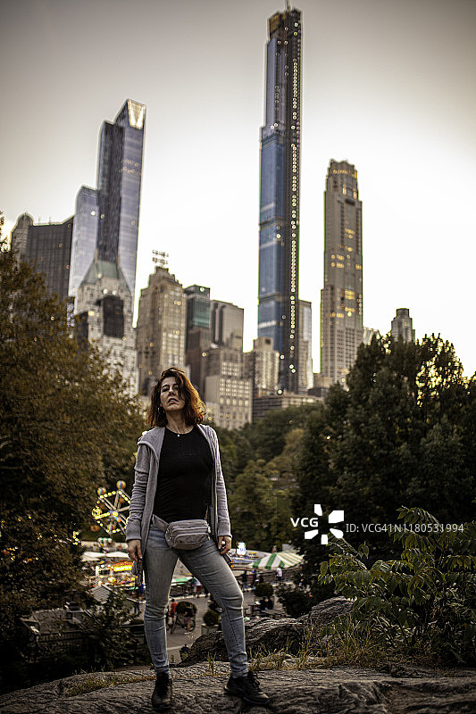 在中央公园拍摄的纽约全景日落上，一位女士摆出了姿势图片素材
