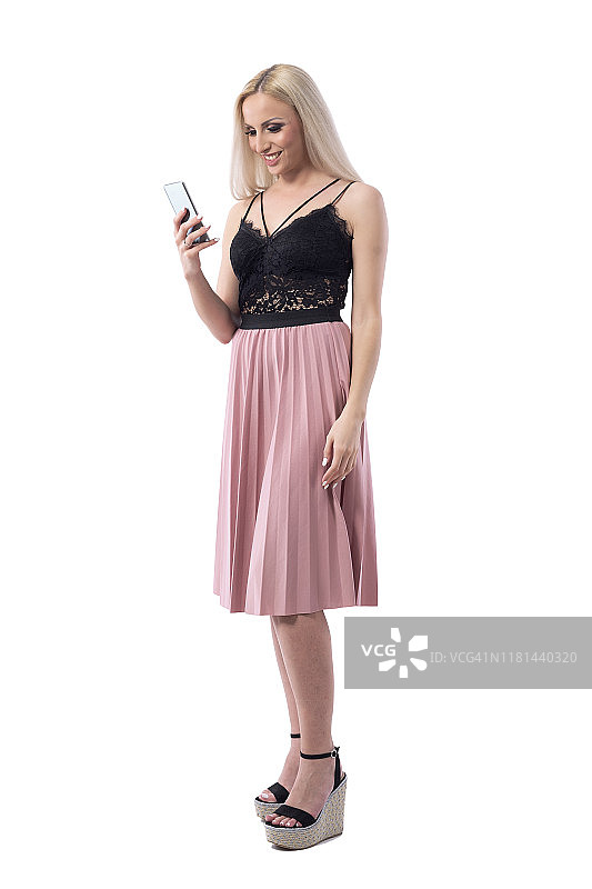 快乐的微笑轻松年轻的金发女人上网使用智能手机在优雅的衣服。图片素材