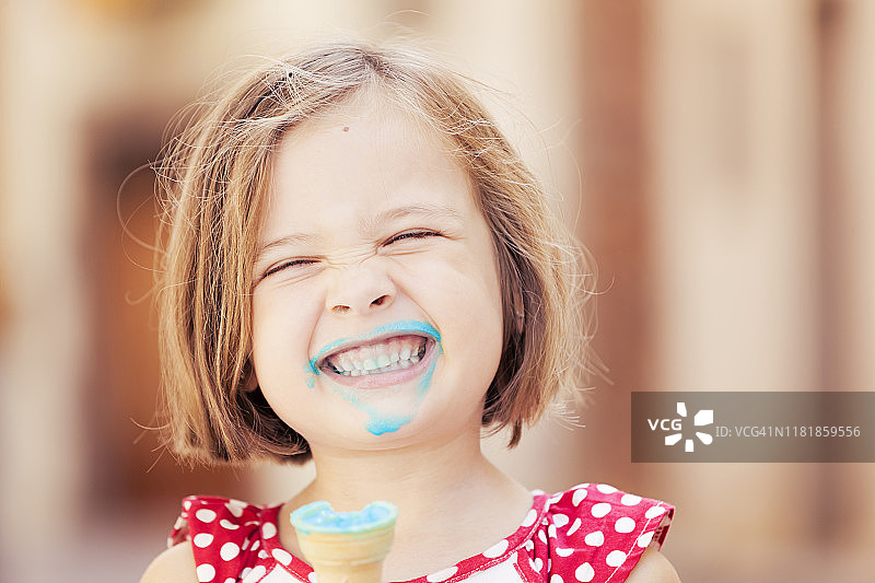 一个快乐的女孩吃着蓝色的冰淇淋图片素材