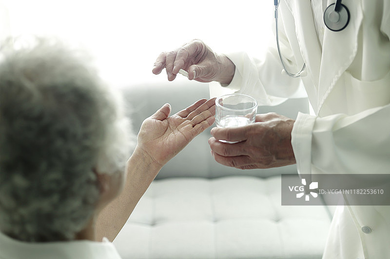 医生给老年妇女提供药物和水图片素材