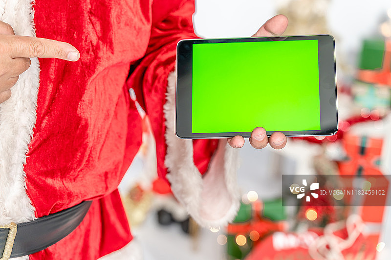 圣诞老人的特写指向数字平板电脑的绿色屏幕，色度键图片素材