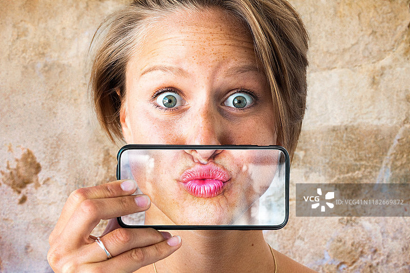 女人在手机上展示接吻的嘴唇图片素材