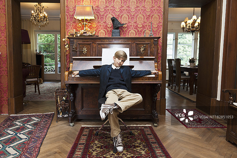 一个男孩摆着一架老式立式钢琴的姿势，姿势很酷图片素材