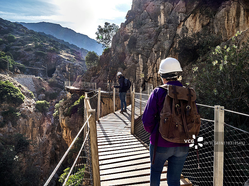 徒步旅行者在大自然中行走在一座木桥上，钉在峡谷的岩壁上达到很高的高度。卡米尼托·德尔雷(《国王大道》)。图片素材