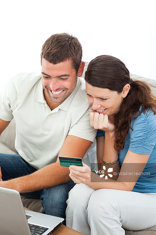 一对可爱的夫妇用他们的笔记本电脑和信用卡在网上购物图片素材