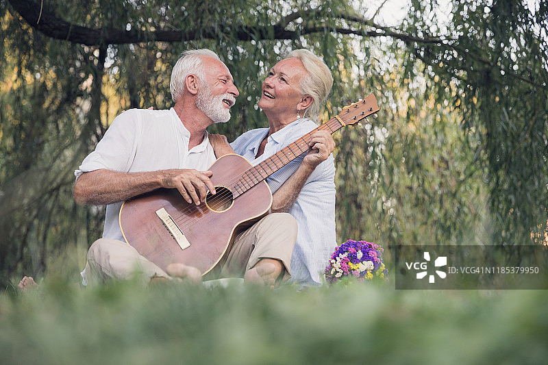 快乐的老女人拥抱她的丈夫弹吉他图片素材