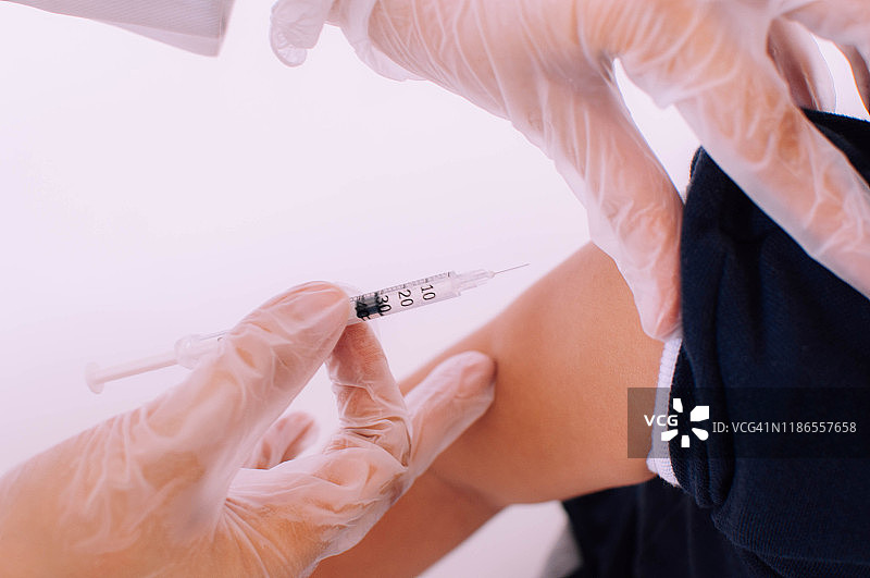 一位年轻的医生正在诊所里给一名男婴注射疫苗图片素材
