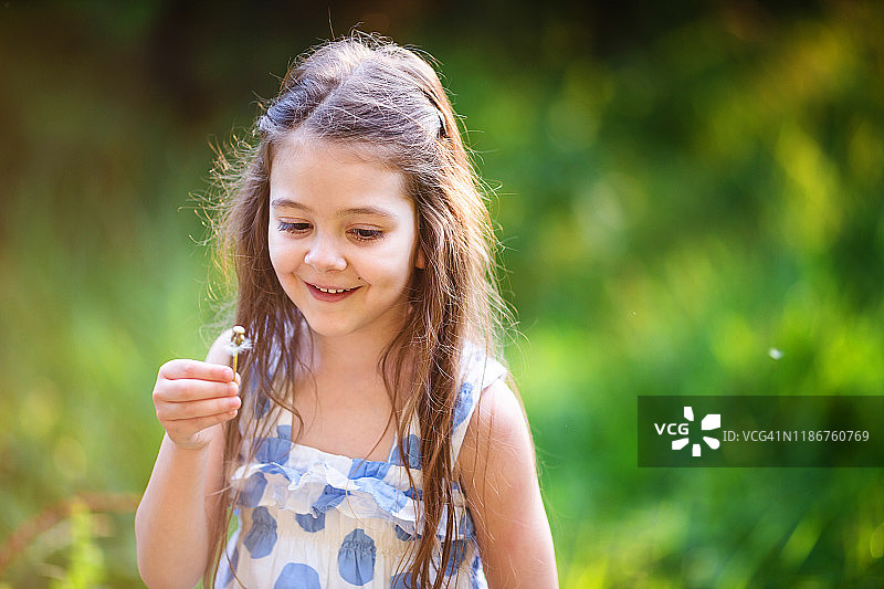 可爱的小女孩在公园里吹蒲公英微笑的特写图片素材