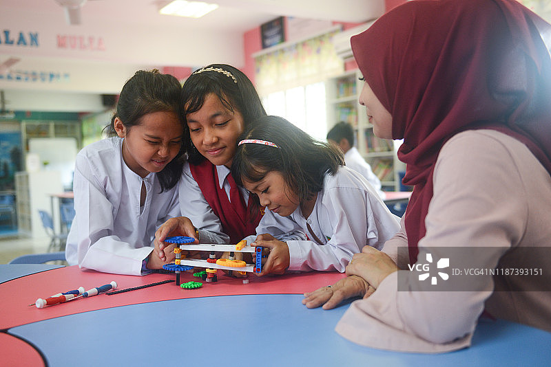 亚洲小学女生和女教师在科学课上制造机器人图片素材