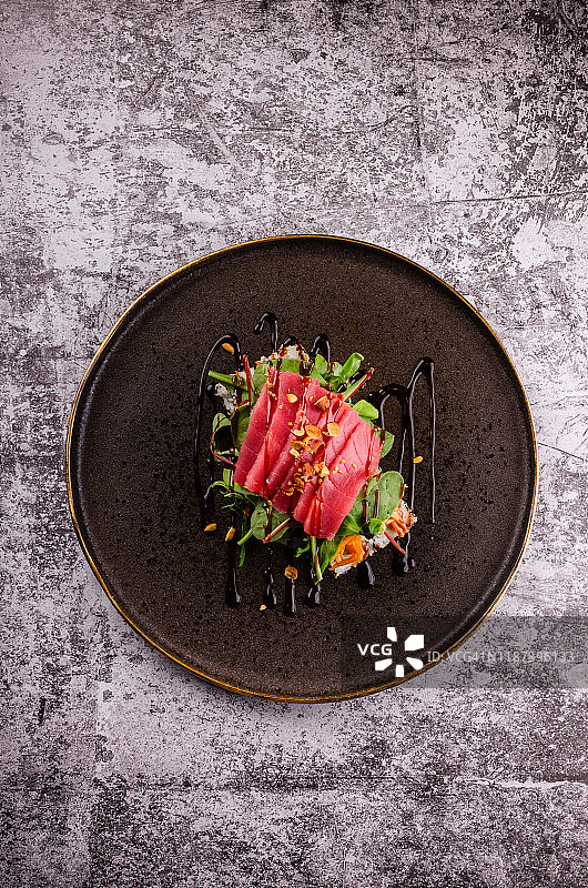 俯视图近距离的生鱼片寿司与生金枪鱼牛排，鳄梨，黄瓜和奶酪费城和大豆在优雅的黑色盘子在混凝土背景。现代日本料理菜单。图片素材