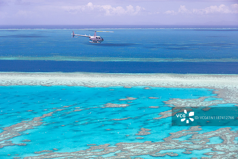 直升机载着游客飞过大堡礁，水面上是地平线。图片素材