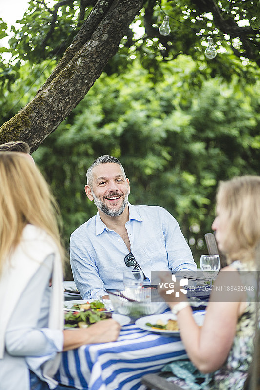 快乐的人享受与朋友在餐桌上的花园聚会图片素材