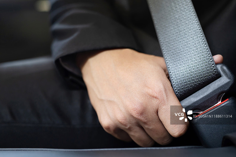 近距离的人商务人员手系安全带在汽车上安全行驶前。交通旅游概念。软的焦点。图片素材