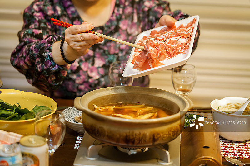 亚洲妇女在家享受中国传统火锅。图片素材