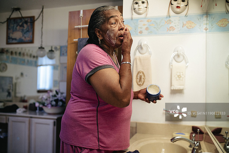 年长的黑人妇女正在擦面霜图片素材