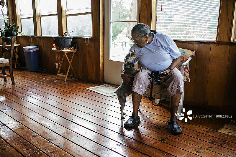 年长的黑人妇女拍着家里的狗图片素材